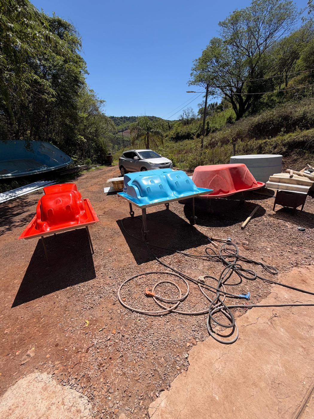 Spas e banheiras coloridos no pátio da fábrica Hidroplas, com o morro ao fundo